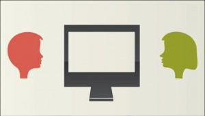 Two people facing each other near a computer screen