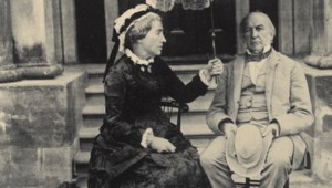 A Victorian woman shelters a man from the sun.