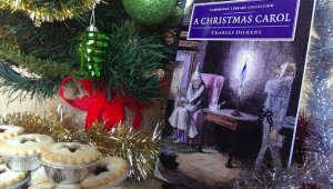 A Christmas Carol by Charles Dickens, alongside a christmas tree, tinsel and mince pies