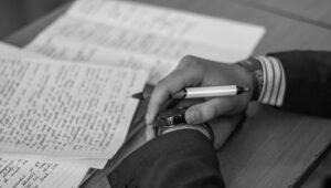 Hands holding a pen next to paper covered in writing